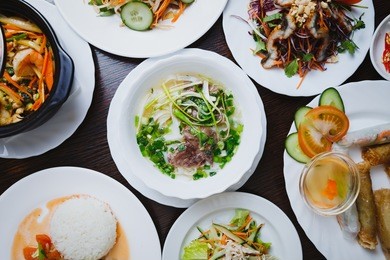 exotic vietnamese cuisine dinner in restaurant.pho bo soup with boiled spicy beef meat,seafood salad& fresh vegetables on table.delicious chinese food menu in cafe.asian gourmet lunch top view