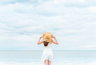 asian woman on white dress standing over the blue sea and sky, feeling relaxing and happy on vacation in summer holiday