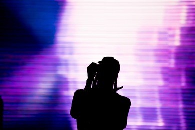 silhouette of an artist singing live on the stage in the front of a colorful background