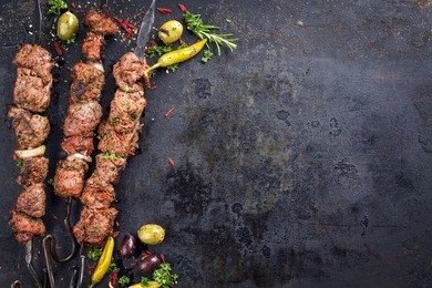 traditional russian shashlik on a barbecue skewer as top view with copy space on old rusty metal sheet 
