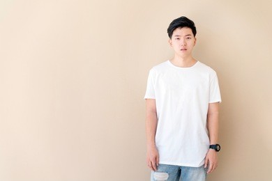 portrait of young asian casual teenage boy indicate blank space on beige background.