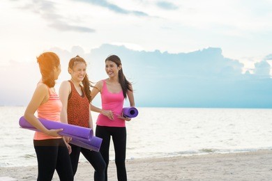 young asian girl group with yoga mat talking after practice relaxation in class exercise  fitness sport for healthy on seaside  modern city at sunrise relax holiday vacation time in summer
