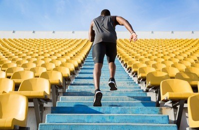 back view of a young man running upstairs at a stadium