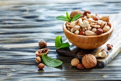 mixed of nuts with a wooden bowl on old table, selective focus.