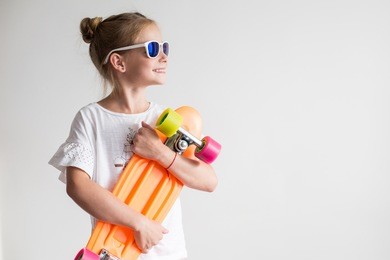 stylish little girl child with skateboard over white background