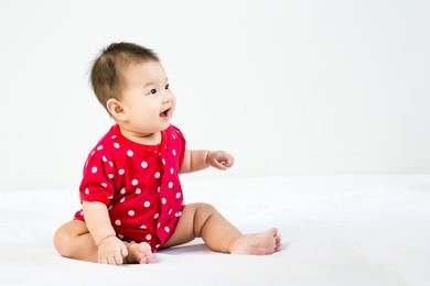 portrait of adorable infant baby girl sitting on the bed with copyspace