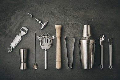 collection of cocktail bar utensils arranged against dark background