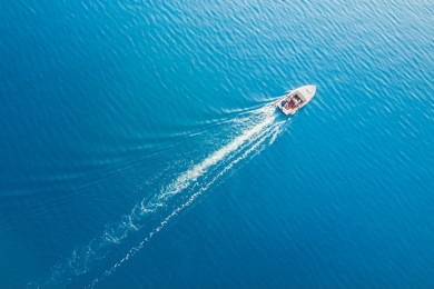 top view of a white boat sailing in the blue sea