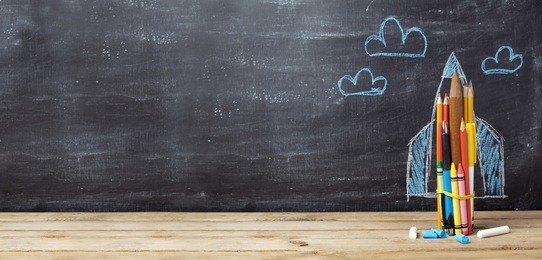 back to school concept with rocket made from pencils over chalkboard background