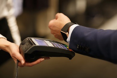 man paying with nfc technology with smart watch application in clothing store, close-up, point of view, shallow depth of field