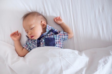 cute little asian 18 months / 1 year old toddler baby boy child sleeping in bed under blanket in bedroom, peaceful kid lying on bed while sleeping, daytime sleep concept,  kid sleeping with copy space