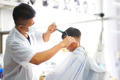 an asian boy doing hair cutting at the barber