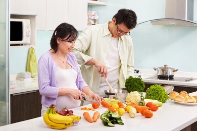 asian couple ( pregnant wife ) busy preparing food in kitchen