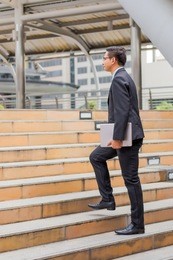 business man with his laptop going up the stairs  in a rush hour to work . hurry time.