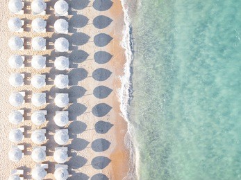 aerial view of amazing beach with white umbrellas and turquoise sea at sunset. mediterranean sea, sardinia, italy.
