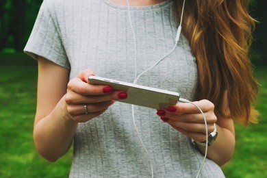 woman, using a smart phone and headphones in the hands, outdoors