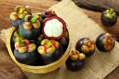 thai fruit : mangosteen is queen of fruits. organic fruit in the basket. fresh mangosteens on wooden table. selective focus. top view of mangosteens.