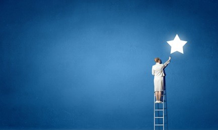 businesswoman on ladder reaching star