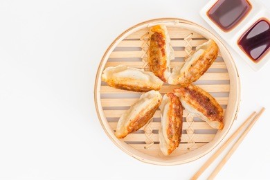 japanese food, gyoza dumplings in bamboo basket, serve with chopsticks isolated on a white background. top view with copy space and text.