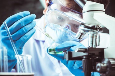 conical flask in scientist hand with microscope and lab glassware background, laboratory research concept
