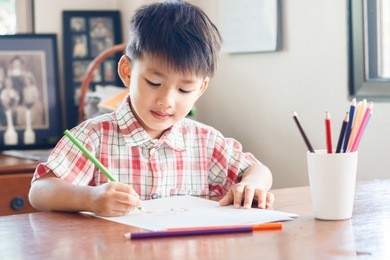 little asian child drawing at home,a boy holding pencil and drawing