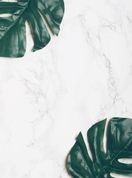 big green tropical leaves on white marble background. flat lay. top view. copy space.
