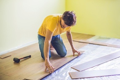 man installing new wooden laminate flooring on a warm film floor. infrared floor heating system under laminate floor