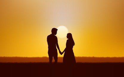 silhouette couple man and woman holding hand walking together under sunset sky background