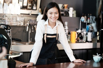 young asian women barista standing with smiling face in font of cafe counter background, small business owner, food and drink industry concept
