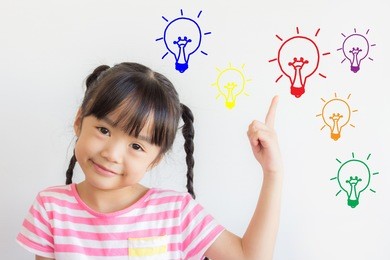asian child point upper and smile happily on white background with some colorful picture of the electric bulbs ,mean that she got some ideas