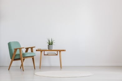 wooden table with fresh plant and book in a room with round carpet