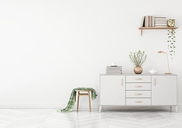 clean living room interior with chest of drawers, stool, plaid and shelf with books on white wall background. 3d rendering.