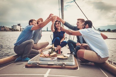 happy friends eating fruits and drinking on a yacht