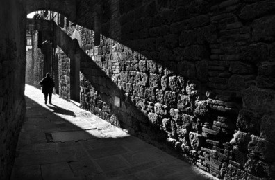 silhouette of a pedestrian in a small street of san gimignano , italy, black and white photography