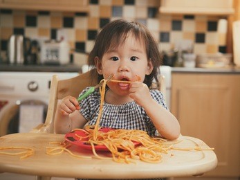 baby girl eating messy spaghetti