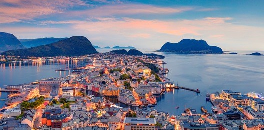 from the bird's eye view of alesund port town on the west coast of norway, at the entrance to the geirangerfjord. colorful sunset in the north. traveling concept background.
