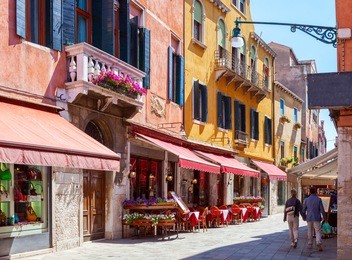 colorful cozy street with tables of cafe at  a sunny morning, venice, italy.    