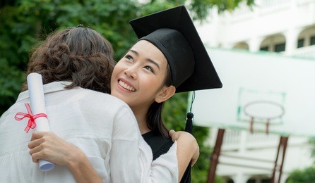young beautiful female graduate hugging her mother at graduation ceremony, pretty female graduate with her father at university graduation,congratulate, age 20-30 years.

