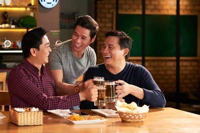 happy mature friends toasting with beer glasses