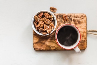 pecan nuts in a bowl and hot coffee, top view