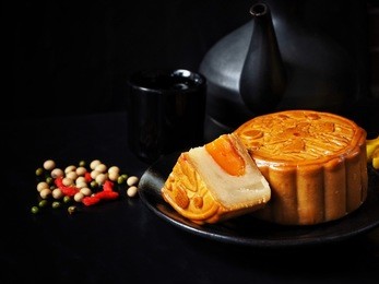 festival moon cake with hot tea on black background