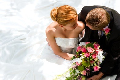 wedding couple hugging, the bride holding a bouquet of flowers in her hand, the groom embracing her