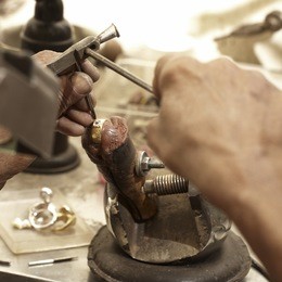 hardworking goldsmith working on an unfinished 22 carat gold ring with his aged hands