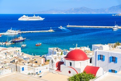 typical greek white church with red dome and view of mykonos port, mykonos island, cyclades, greece