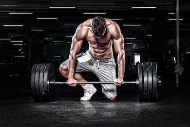 athletic shirtless young sports man - fitness model with barbell in gym.