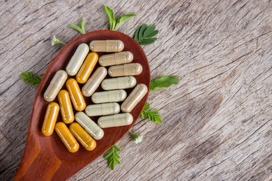 supplement herbal capsules on wooden spoon from various herbs, healthy eating lifestyle with natural remedy medical