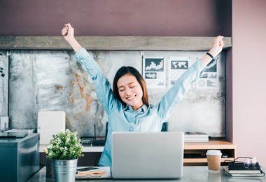 asian creative designer raise arm up and close eye in front of laptop computer on desk,relax from hard work in office