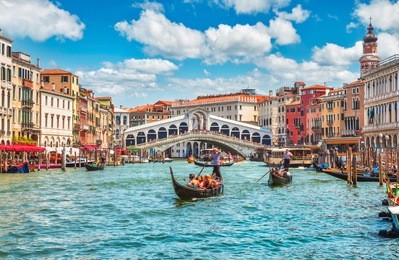 bridge rialto on grand canal famous landmark panoramic view venice italy with blue sky white cloud and gondola boat water.