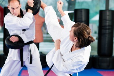people in a gym in martial arts training exercising taekwondo, both have a black belt