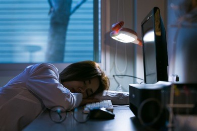 sleepy exhausted woman working at office desk with her laptop. overtime working concept